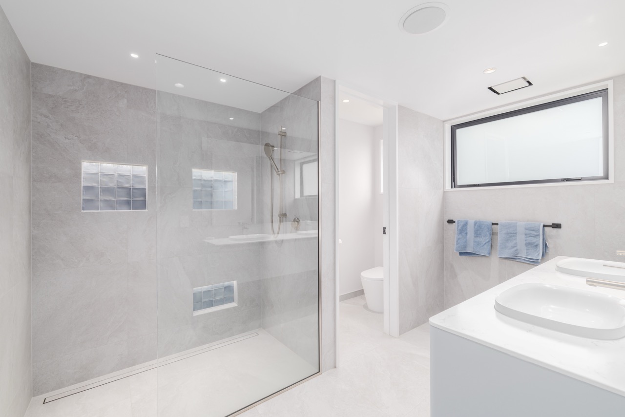 Main bathroom with walk-in shower, marble tile, dual niches, and double vanity