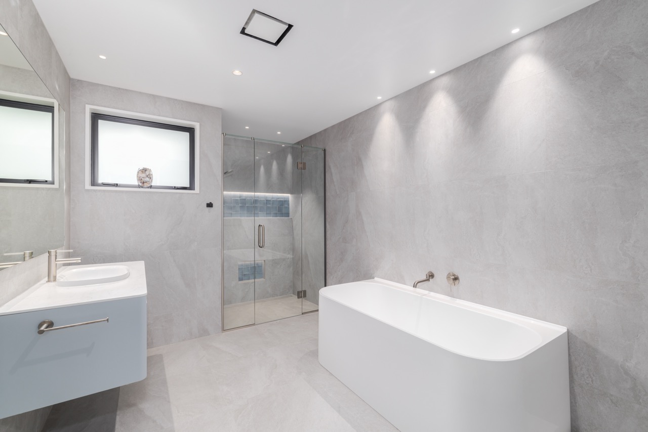 Ensuite bathroom with freestanding bath, marble-look tile, and frameless glass shower