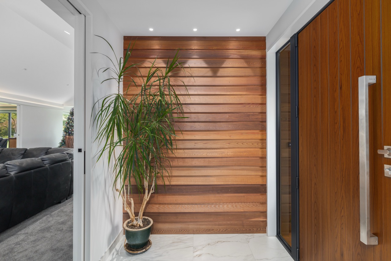 Entry foyer with horizontal cedar slat feature wall and timber front door