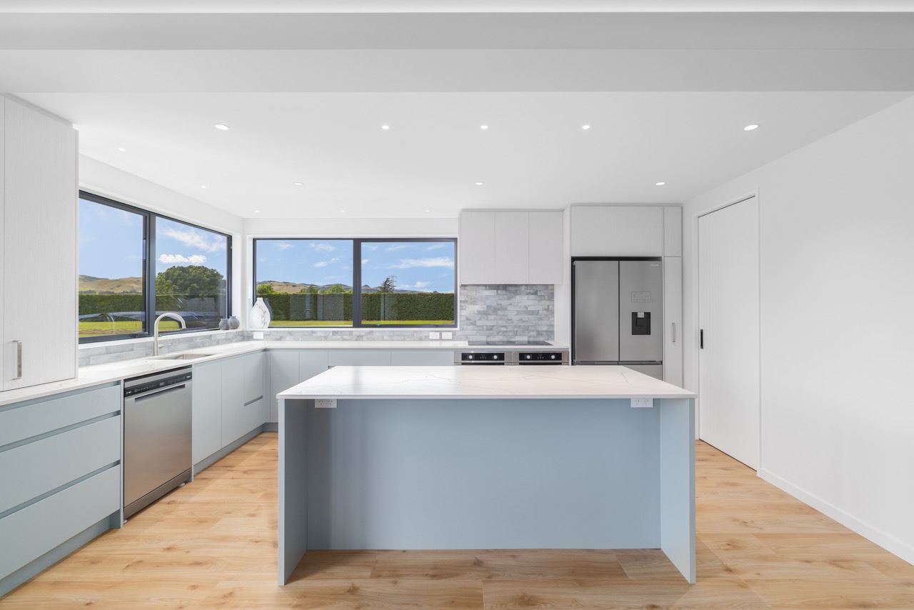 Kitchen from alternate angle showing oak flooring and expansive windows