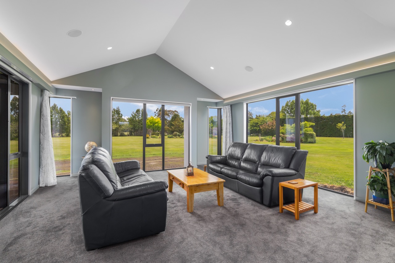 Second living room with sage walls, vaulted ceiling, and floor-to-ceiling glazing
