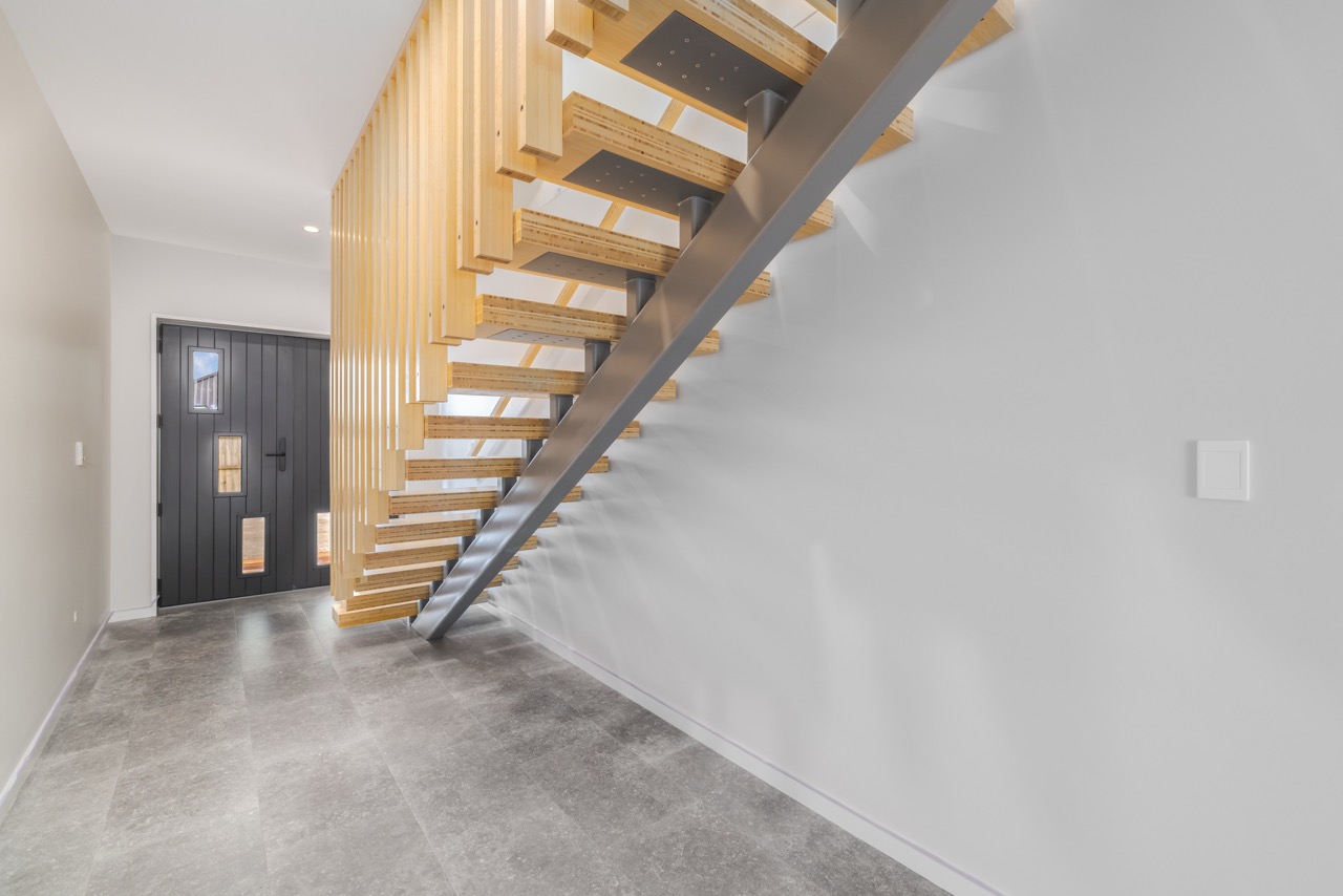 Entry foyer with floating bamboo timber staircase and dark front door