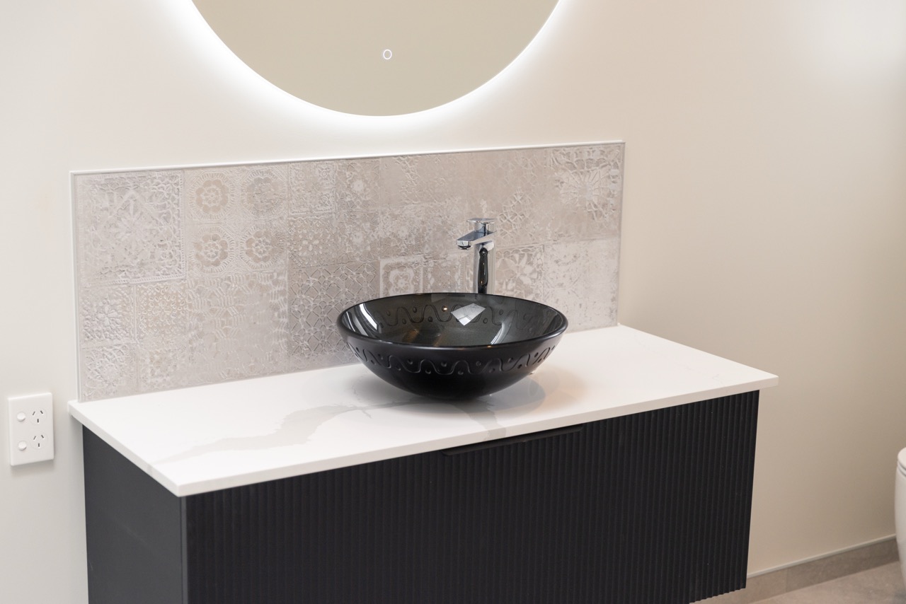 Vessel basin on white stone bench with patterned tile splashback