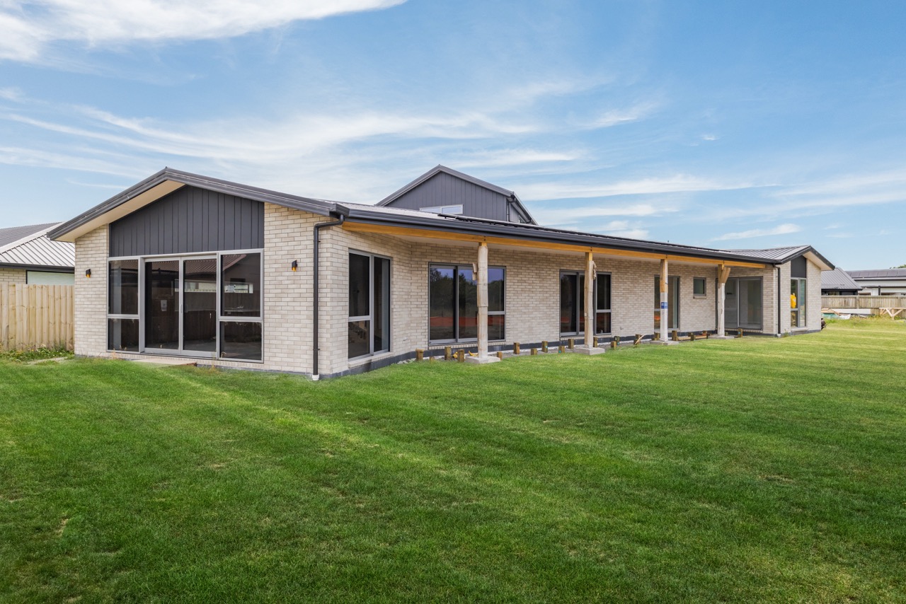 Rear exterior showing covered veranda and expansive lawns