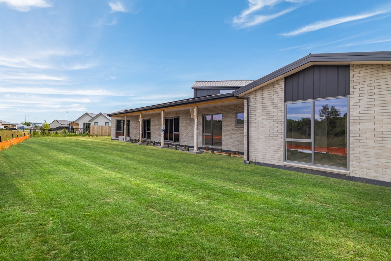 Side exterior showing brick and cladding with manicured lawn