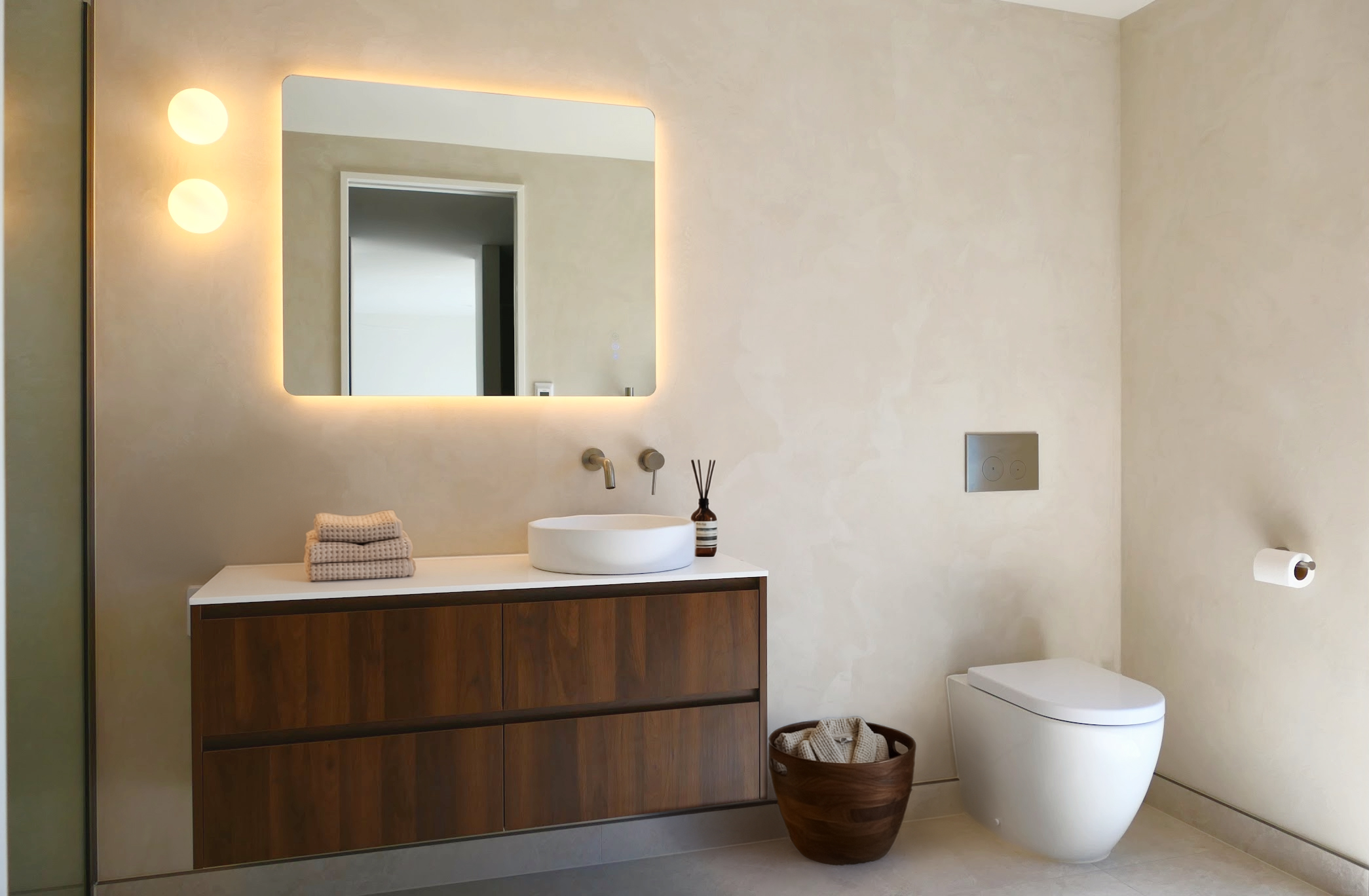 Modern bathroom renovation with floating walnut vanity and backlit mirror