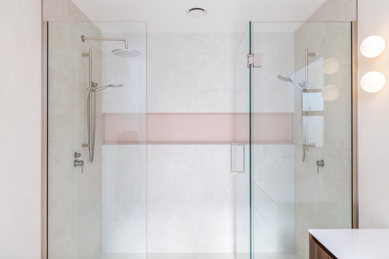 Ensuite double shower with glass screens, beige tile, and pink mosaic feature band