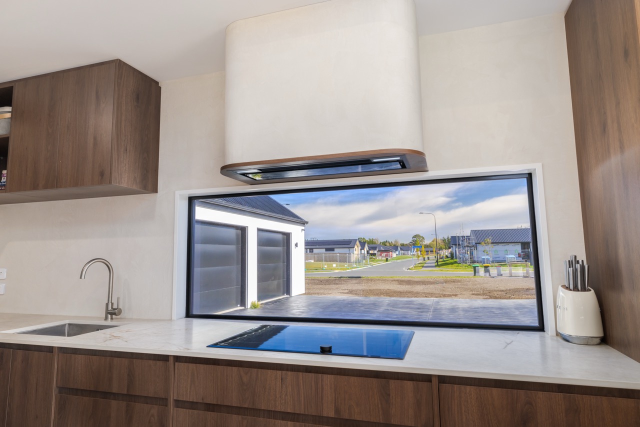 Kitchen splashback window framed by walnut cabinetry, stone bench, and gas cooktop