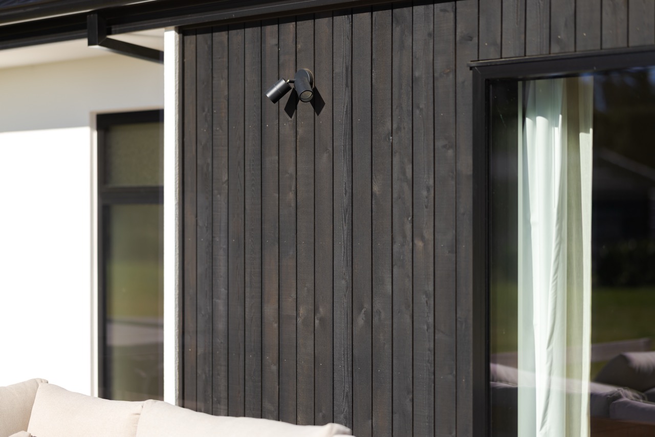 Black vertical shiplap timber cladding detail with wall-mounted exterior light