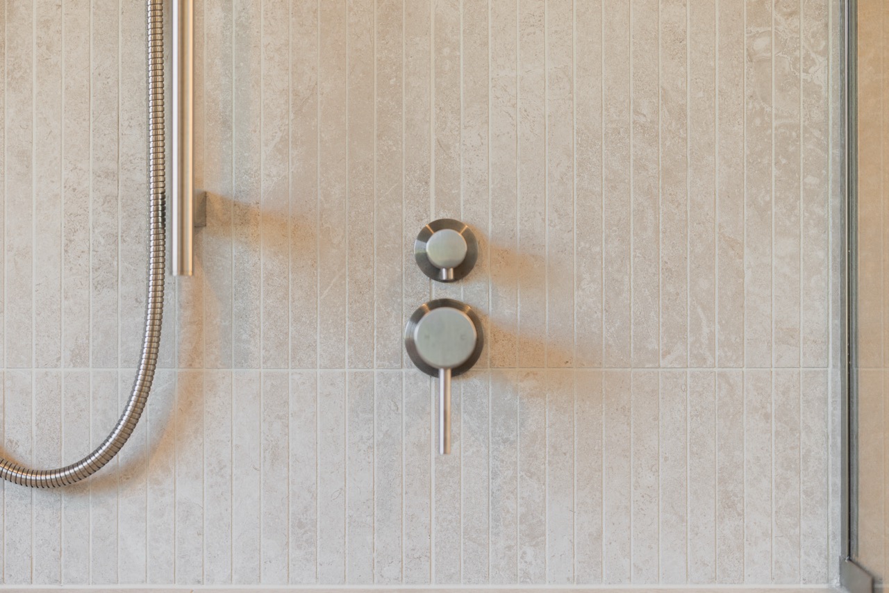 Shower mixer detail on vertical pencil tile with handheld and rail