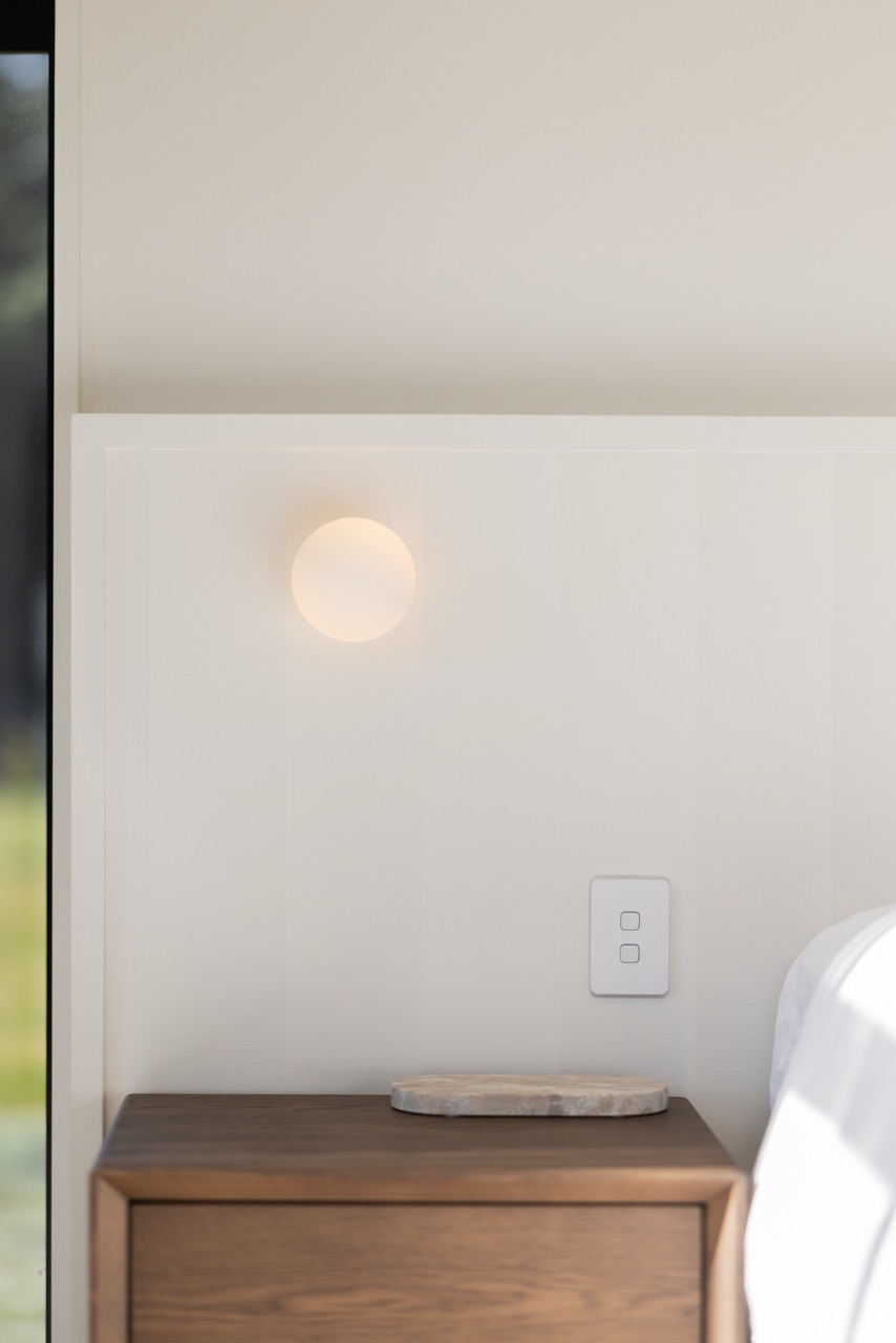 Wall sconce close-up beside the master bed with marble coaster on nightstand