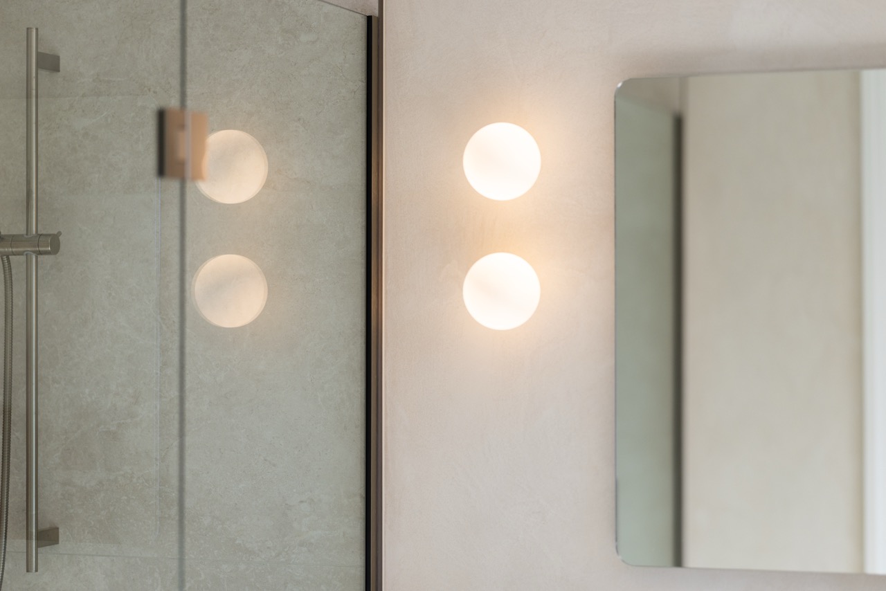 Designer twin globe wall sconces in the ensuite reflected in mirror