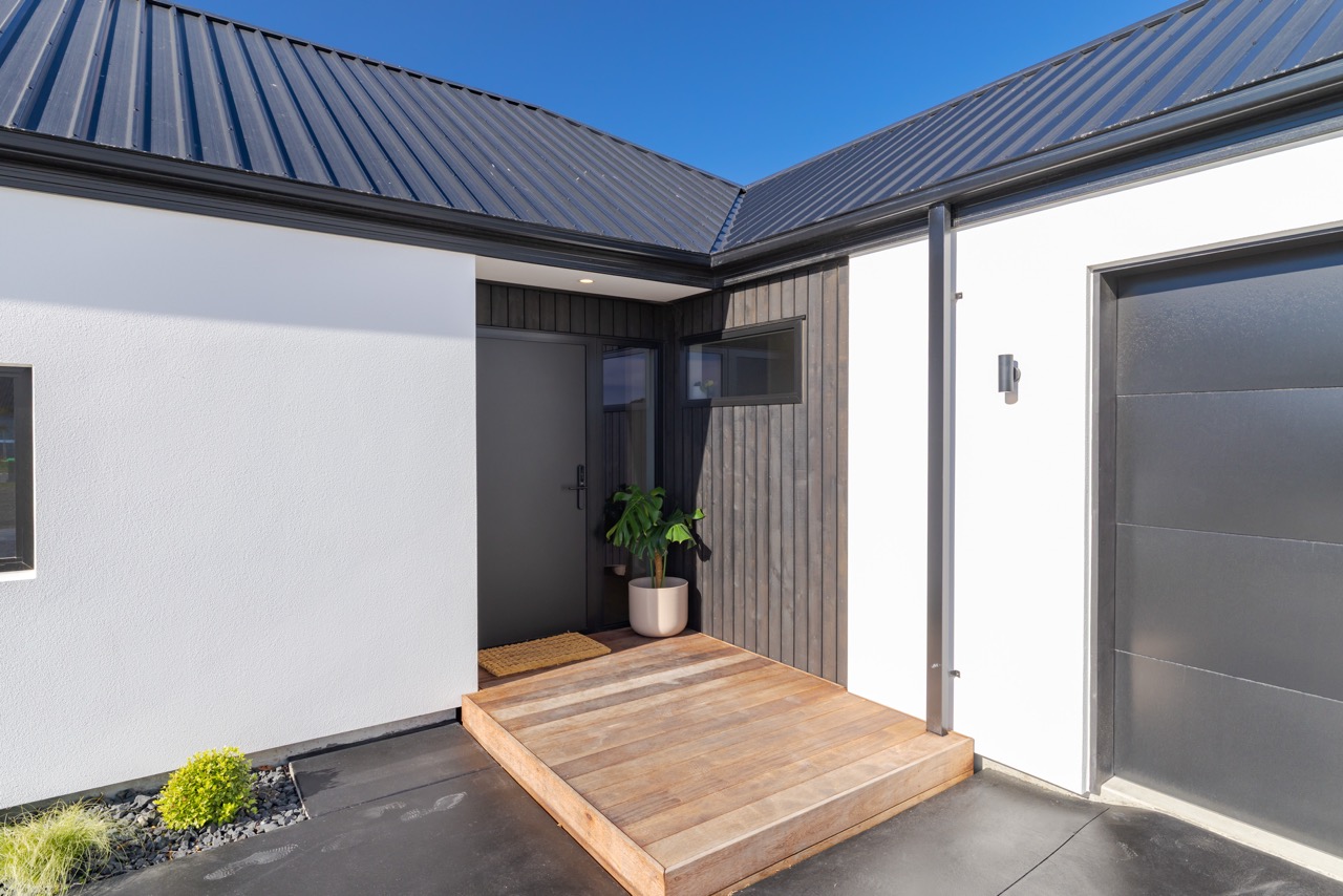 Front entry — black door, vertical timber feature panel, and hardwood step
